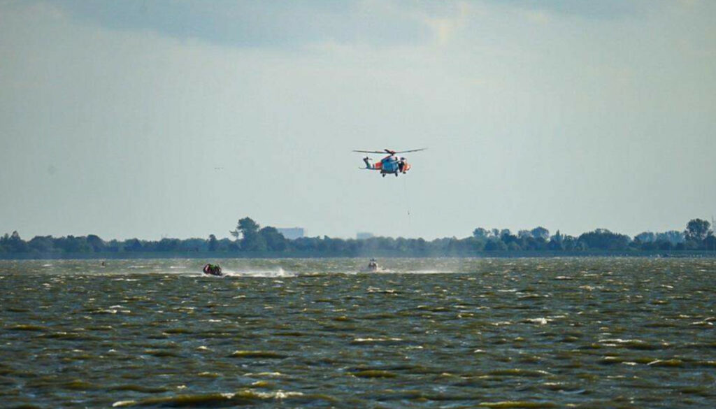 Er wordt met een helikopter en reddingboten gezocht naar de drenkeling.