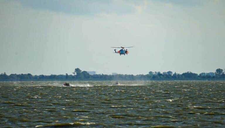 Er wordt met een helikopter en reddingboten gezocht naar de drenkeling.